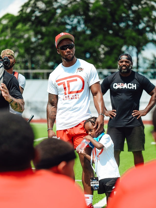 Chester Tre' Rogers in a TD Combine tee with young athletes on the field