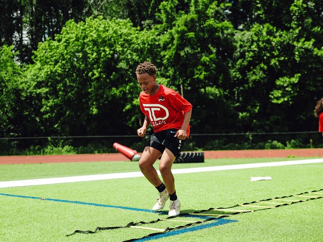 Young athlete running an agility ladder drill in a TD Combine jersey
